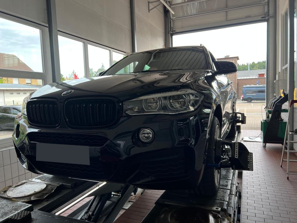 Schwarzer SUV auf dem Prüfstand einer Werkstatt, an den Rädern sind Messköpfe befestigt