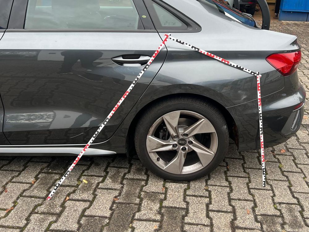 Graue Limousine von der Seite, an Tür und Seitenwand hinten sind rot-weiße Fotomaßstäbe angelegt